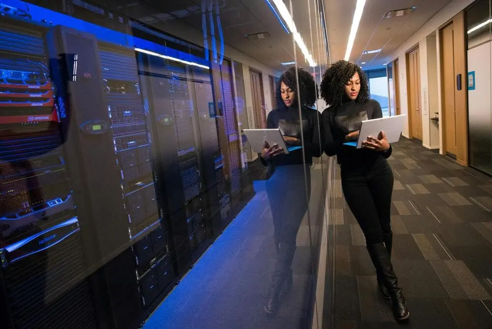 Young woman with a laptop near an AI server