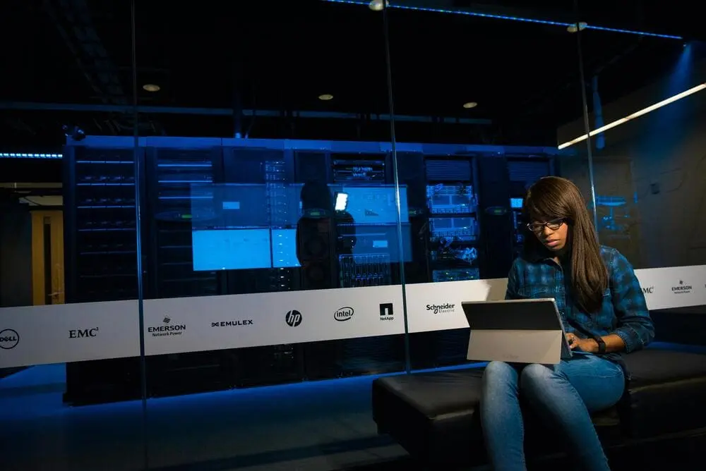 Woman working on a laptop with IT servers in the background