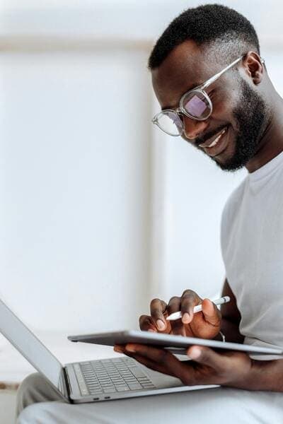 Smiling man with a notebook, interacts with a tablet